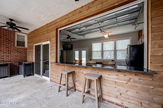 kitchen featuring a peninsula, ceiling fan, concrete flooring, and refrigerator