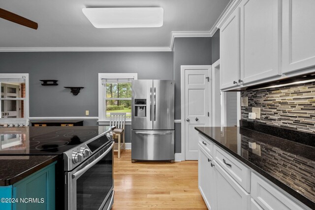 kitchen featuring light wood-type flooring, appliances with stainless steel finishes, dark stone countertops, white cabinetry, and decorative backsplash