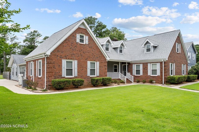 cape cod-style house with covered porch, brick siding, a front lawn, and cooling unit