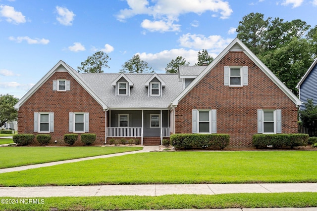 view of front of property with a porch, a front yard, and brick siding