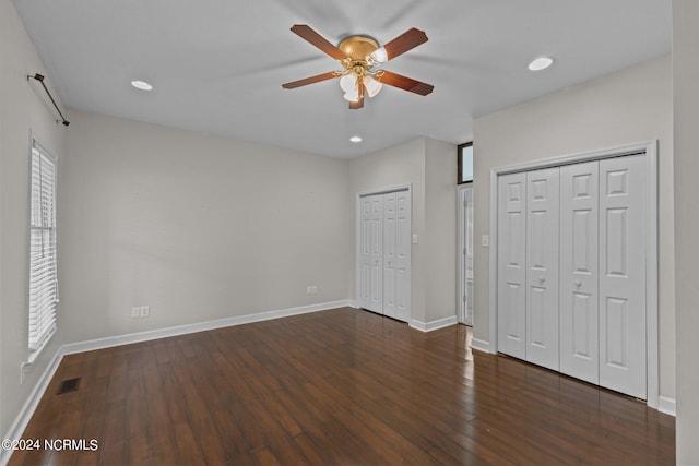 unfurnished bedroom with hardwood / wood-style floors, two closets, and ceiling fan