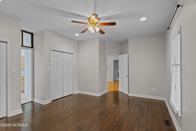 unfurnished bedroom with ceiling fan, multiple windows, hardwood / wood-style flooring, and a closet