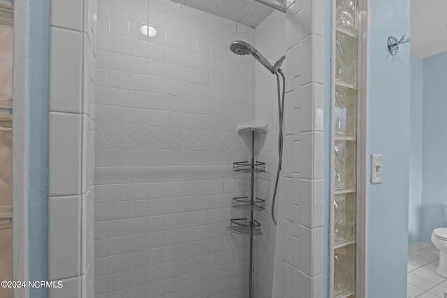 bathroom featuring tiled shower, toilet, and tile patterned flooring