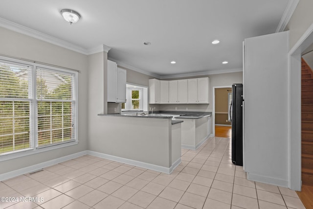 kitchen with light hardwood / wood-style flooring, kitchen peninsula, white cabinets, crown molding, and black fridge