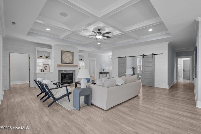 living area featuring coffered ceiling, a barn door, a premium fireplace, and light wood-style flooring