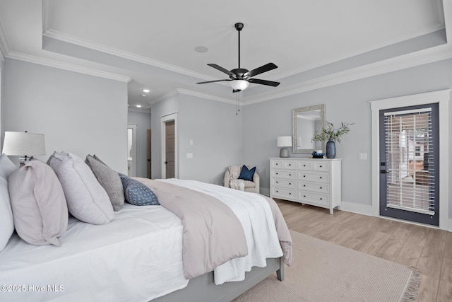 bedroom featuring a raised ceiling, crown molding, light wood-style flooring, and baseboards