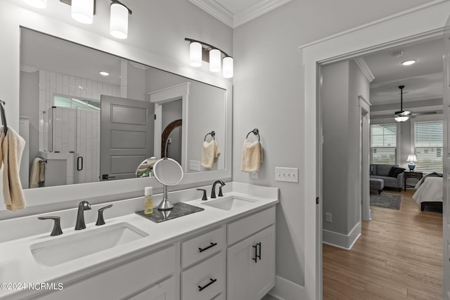 bathroom with wood finished floors, ornamental molding, a stall shower, and a sink