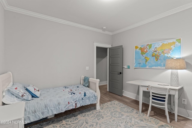 bedroom with baseboards, ornamental molding, and wood finished floors