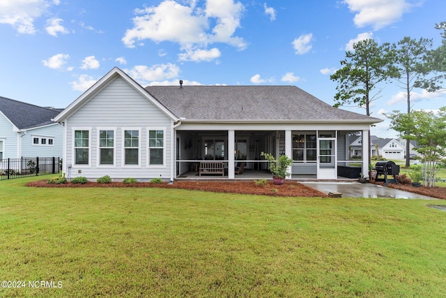 rear view of property with roof with shingles, a lawn, fence, and a sunroom