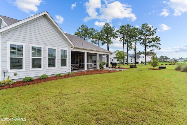 back of house featuring a sunroom, roof with shingles, and a yard