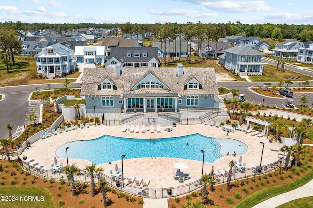 community pool with a patio, fence, and a residential view