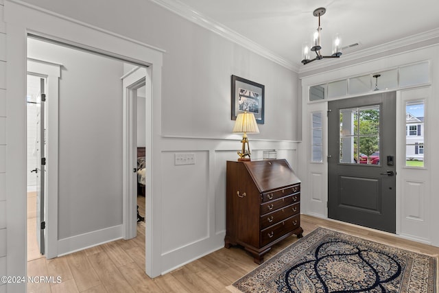 entrance foyer featuring a decorative wall, a notable chandelier, visible vents, ornamental molding, and light wood-type flooring