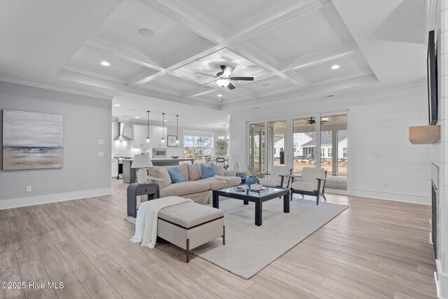 living room with ornamental molding, light wood-type flooring, coffered ceiling, and a ceiling fan