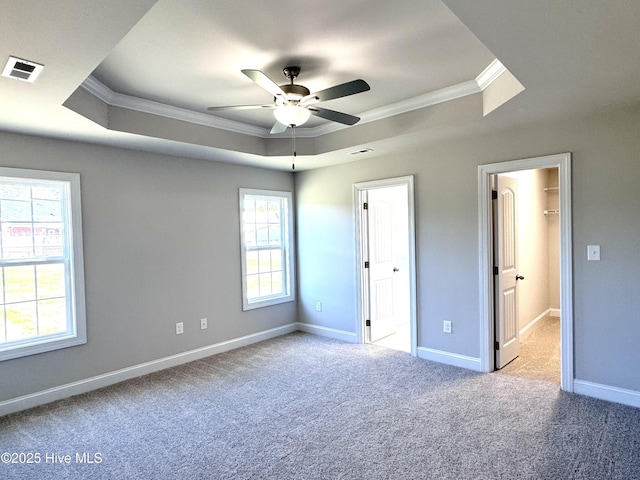 unfurnished bedroom with light colored carpet, a raised ceiling, visible vents, and crown molding