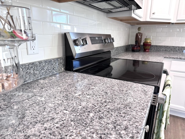 kitchen with electric range, decorative backsplash, white cabinetry, light stone countertops, and extractor fan