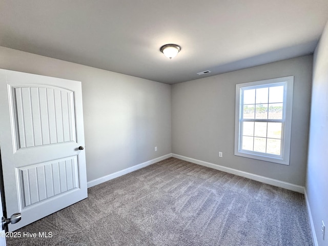 unfurnished room featuring baseboards, visible vents, and carpet flooring