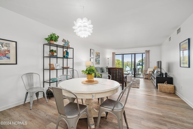 dining area featuring baseboards, visible vents, light wood-style flooring, and a notable chandelier