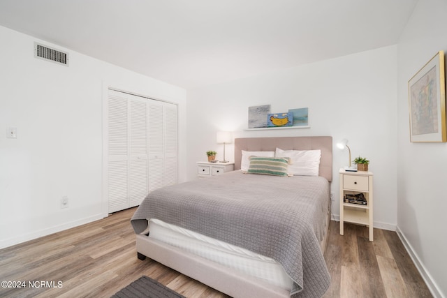 bedroom featuring a closet, visible vents, baseboards, and wood finished floors