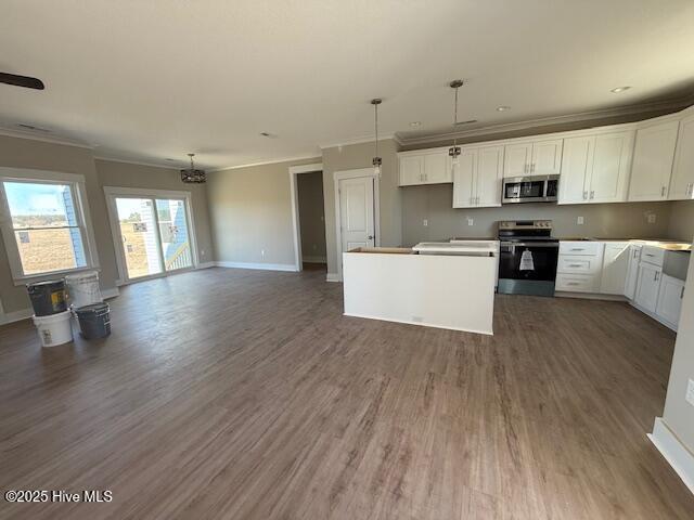 kitchen with hanging light fixtures, a kitchen island, white cabinets, and appliances with stainless steel finishes