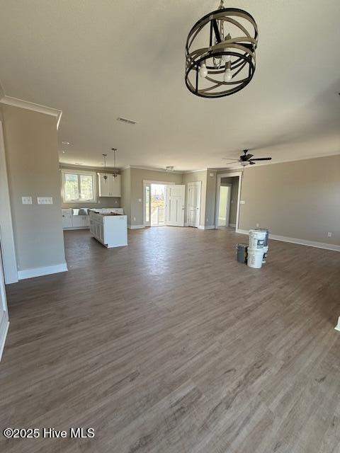 unfurnished living room featuring dark hardwood / wood-style flooring, ornamental molding, and ceiling fan