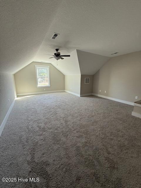 bonus room with ceiling fan, vaulted ceiling, a textured ceiling, and carpet