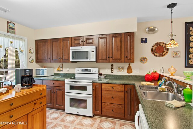 kitchen featuring pendant lighting, white appliances, and sink