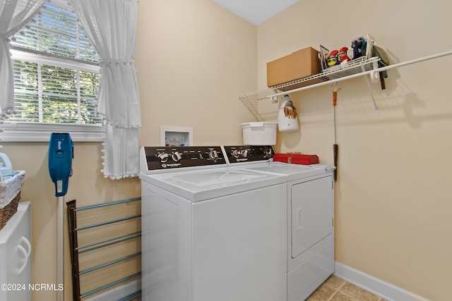 laundry room with independent washer and dryer and light tile patterned floors