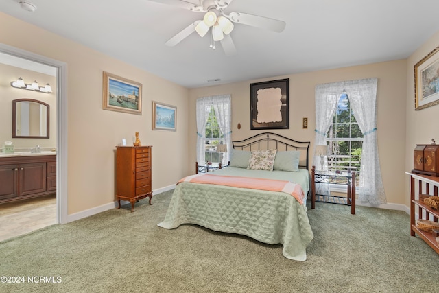 carpeted bedroom with ensuite bath, ceiling fan, and sink