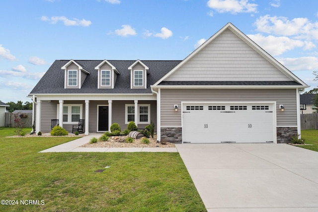 view of front of property featuring a front lawn, covered porch, and a garage