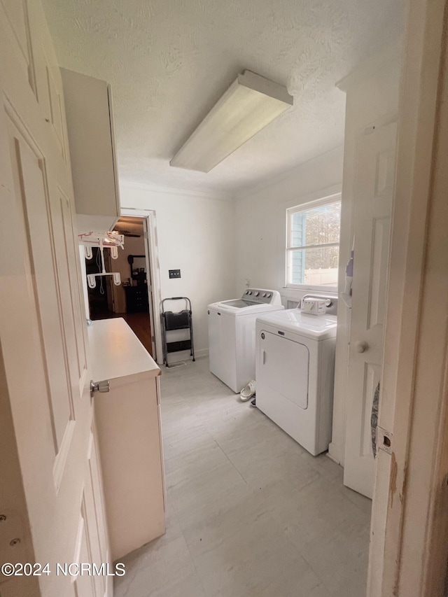 laundry area featuring a textured ceiling, light tile patterned flooring, and washing machine and clothes dryer