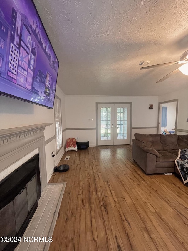 living room featuring a textured ceiling, ceiling fan, hardwood / wood-style flooring, and french doors