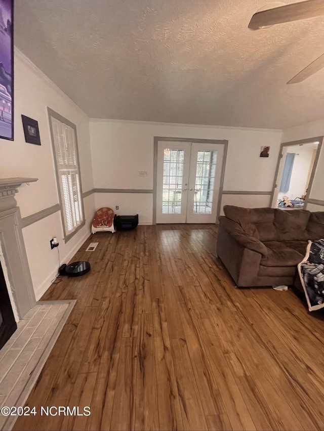 unfurnished living room featuring hardwood / wood-style floors, french doors, ceiling fan, and a textured ceiling