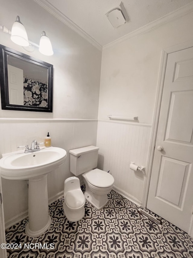 bathroom featuring tile patterned flooring, toilet, and ornamental molding