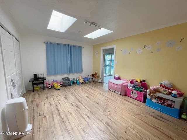 game room with light hardwood / wood-style floors and a skylight