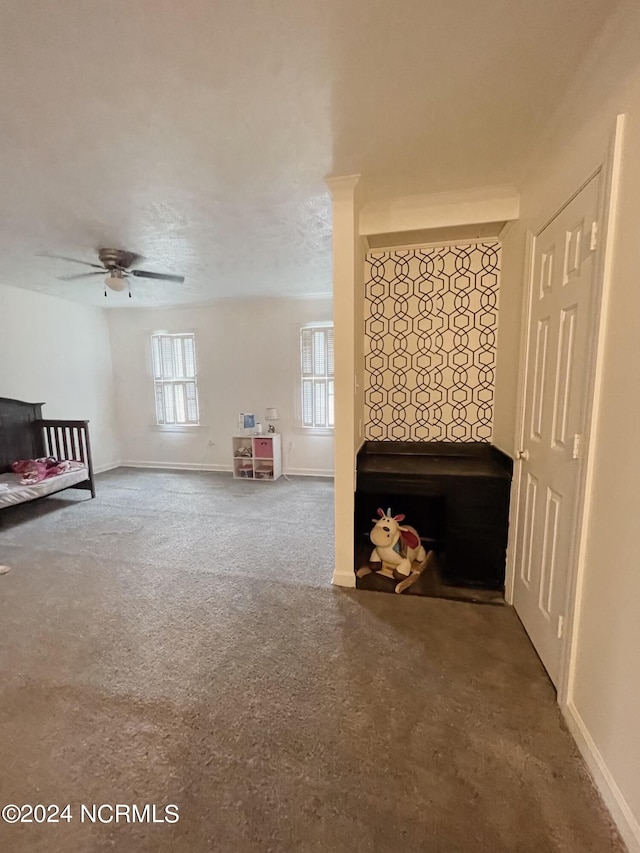 unfurnished living room with ceiling fan and carpet