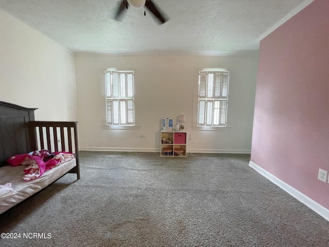 carpeted bedroom featuring ceiling fan, a textured ceiling, and multiple windows