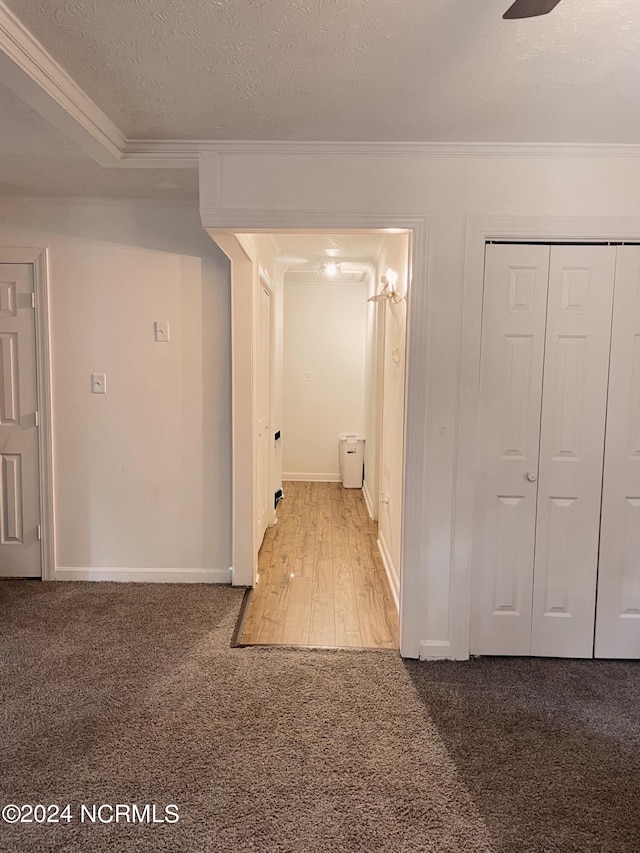 hallway featuring crown molding, a textured ceiling, and carpet flooring