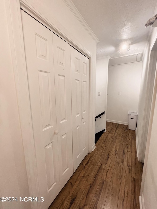 hallway featuring dark hardwood / wood-style flooring, a textured ceiling, and ornamental molding