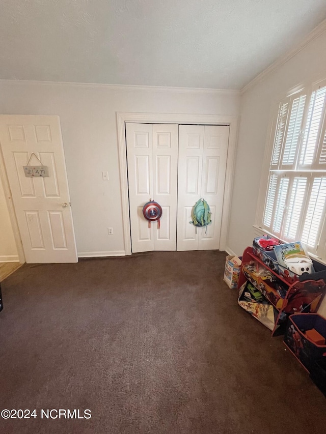 unfurnished bedroom with dark carpet, ornamental molding, and a closet