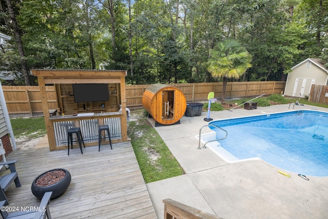 view of swimming pool with an outdoor bar, an outdoor fire pit, and a wooden deck