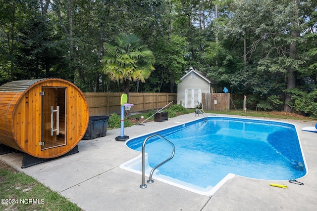 view of pool with a shed and a patio area