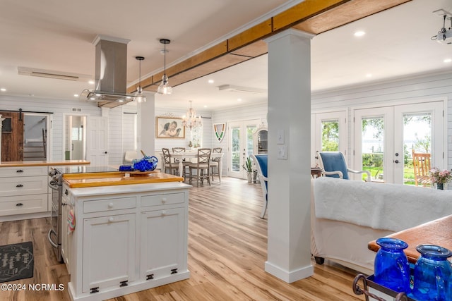 511 N A St, Bridgeton, NC 28519 - kitchen featuring french doors, island exhaust hood, white cabinetry, light wood-style floors, and light countertops