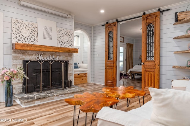 511 N A St, Bridgeton, NC 28519 - living room with a fireplace with raised hearth, wood finished floors, arched walkways, crown molding, and a barn door