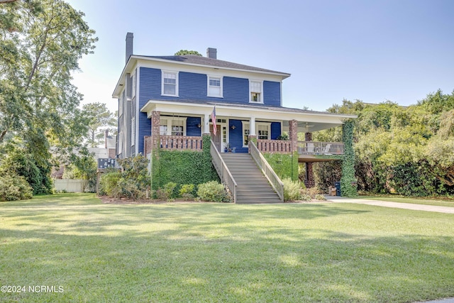 view of front of house featuring stairs, a chimney, a front lawn, and a porch