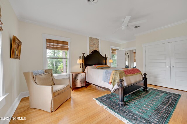 bedroom with hardwood / wood-style flooring, crown molding, ceiling fan, and a closet