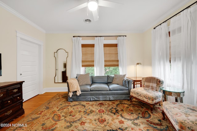 living room featuring ornamental molding, ceiling fan, and light wood-type flooring