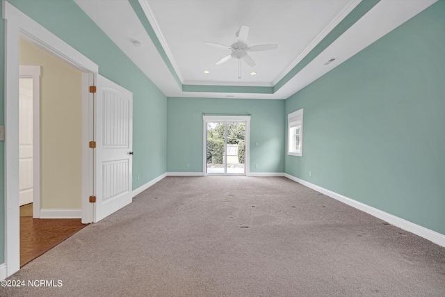 empty room featuring ceiling fan, ornamental molding, a raised ceiling, and carpet flooring