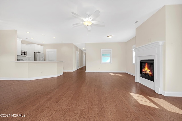 unfurnished living room featuring ceiling fan and dark hardwood / wood-style flooring