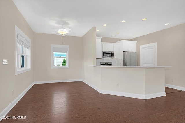 kitchen featuring white cabinetry, dark wood-type flooring, kitchen peninsula, stainless steel appliances, and ceiling fan