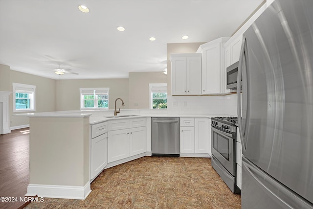 kitchen with white cabinets, kitchen peninsula, appliances with stainless steel finishes, and sink